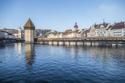 Bridge over river by buildings against sky in city