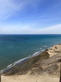 Scenic view of sand dunes and sea against sky