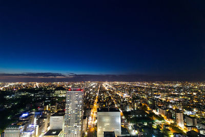 Illuminated cityscape against blue sky