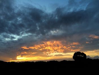 Silhouette landscape against dramatic sky during sunset