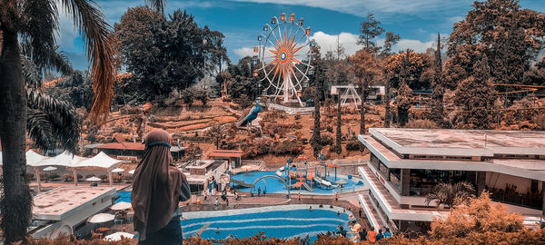 Rear view of people by swimming pool against sky