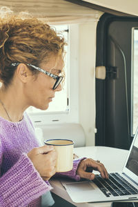 Side view of young woman using laptop at home