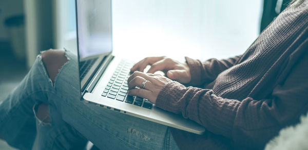 Young woman working on laptop at home. closeup of female hands typing on pc keyboard 