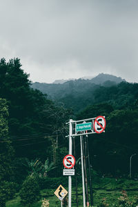 Information sign by road against sky