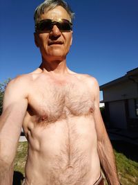 Portrait of shirtless mature man wearing sunglasses during sunny day