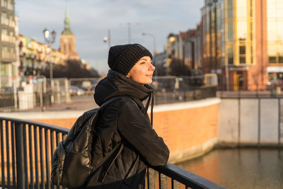 Young woman traveling with black backpack. side view. happy female walking on the city street.