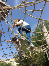 Low angle view of friends climbing on ropes at playground