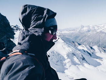 Side view of man in warm clothing standing on snow covered mountain