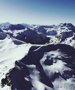Aerial view of snowcapped mountains against clear sky