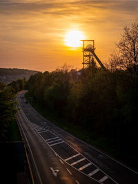 High angle view of empty road by trees against sky during sunset