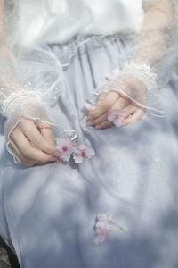 Midsection of woman holding white flower