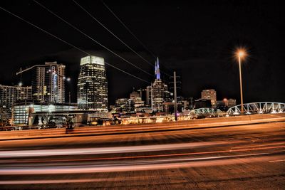 Light trails on road against buildings at night