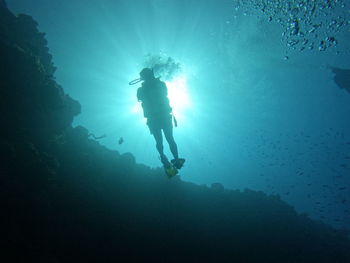 Scuba diver ascending into the sunlight halo after a 24m reef wall dive in the caribbean 