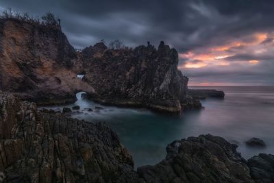 Rock formation on sea against sky during sunset