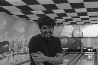 Portrait of cheerful young man standing at bowling alley