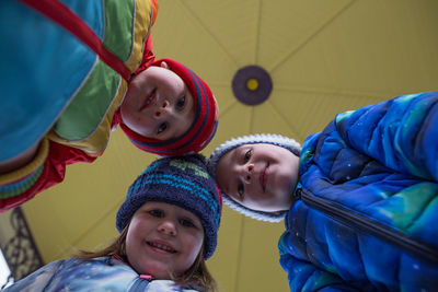 Low angle portrait of siblings against ceiling at home