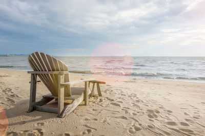 Chair on beach against sky