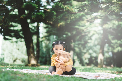 Cute boy sitting on toy against trees