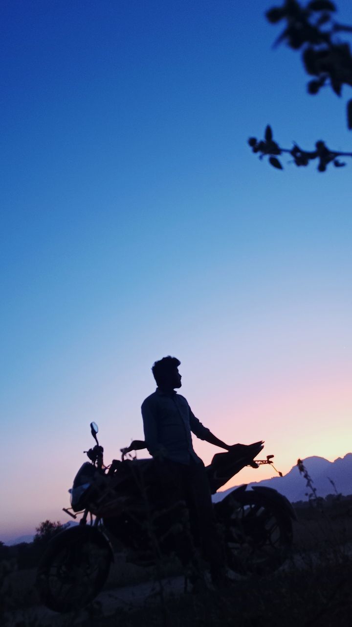 sky, nature, silhouette, one person, adult, clear sky, sitting, mountain, blue, activity, men, leisure activity, sunset, copy space, dusk, adventure, outdoors, full length, beauty in nature, travel, transportation, extreme sports, relaxation, scenics - nature, sunlight, travel destinations