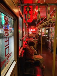 Woman sitting in illuminated bus