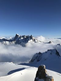 Scenic view of snow covered mountains against blue sky