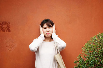 Portrait of a girl standing against orange wall