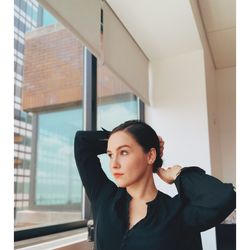 Young woman with hand in hair looking through window