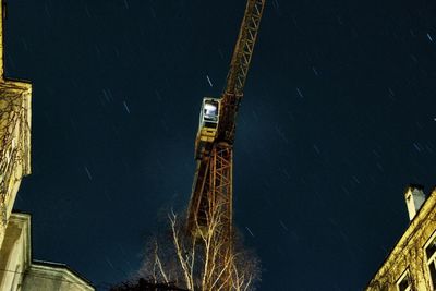 Low angle view of illuminated crane against sky at night