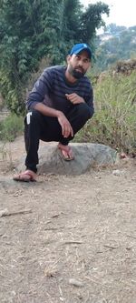 Full length of young man sitting on land