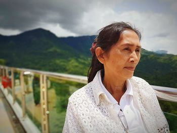 Portrait of woman standing by railing against mountains