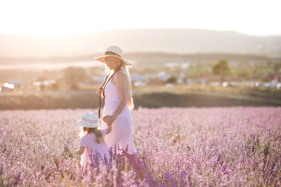 Mother and daughter wearing hat in flowering field