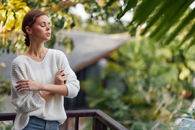 Portrait of young woman standing against trees