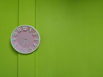 Close-up of clock on green wall