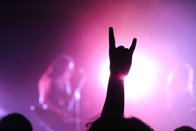 Silhouette cropped hand gesturing at music concert