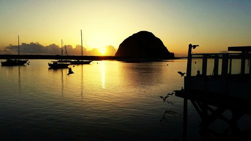 Silhouette boats in sea against clear sky during sunset