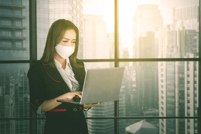 Woman looking away while standing on window