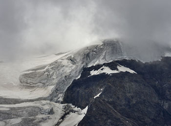 Scenic view of snowcapped mountains and icefall against cloudy  sky