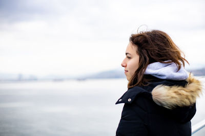 Pensive young girl looking to sea from boat. teenager girl at ferryboat. cold grey sea