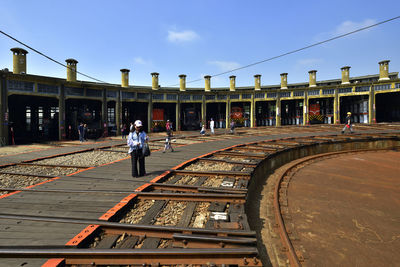 People at railroad station against sky