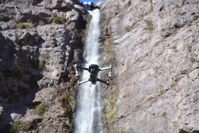 High angle view of drone flying against waterfall