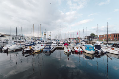 Boats moored at harbor against sky