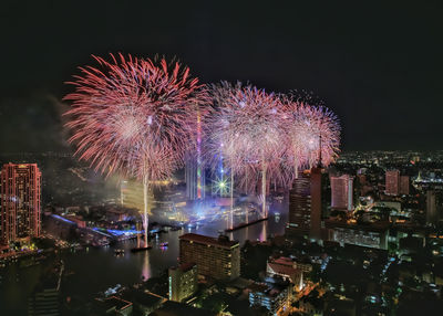 Firework display over illuminated buildings in city at night