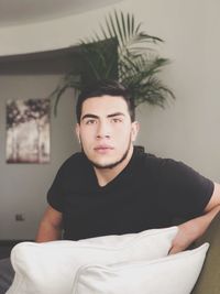 Portrait of young man sitting on sofa at home