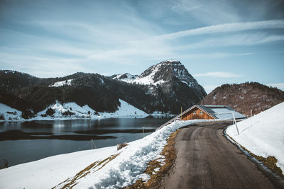 Snow covered mountain by lake against sky