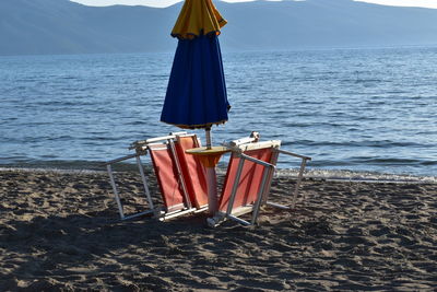 Deck chairs on beach against sky