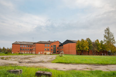 House on field by houses against sky