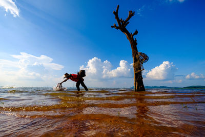 Fisherman fishing in sea against sky