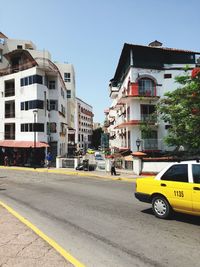 Cars on road by buildings against sky