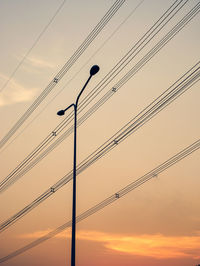 Low angle view of silhouette electricity pylon against sky during sunset