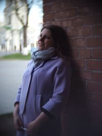 Side view of woman standing against brick wall